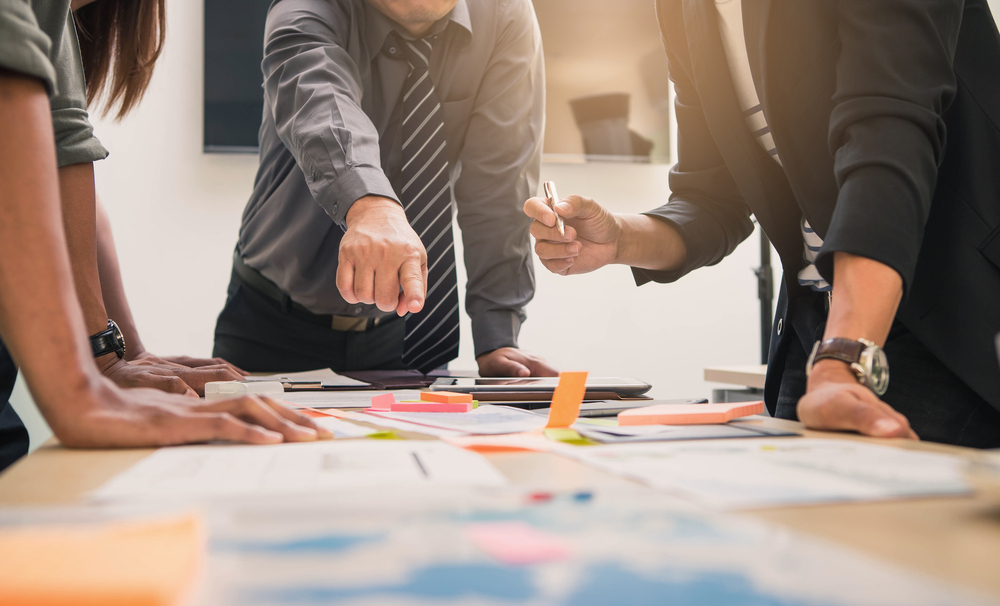 Quel est le rôle du marketing stratégique ? 1 groupe de personnes élaborant une stratégie marketing sur papier