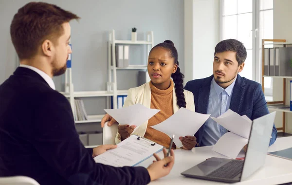 Rebranding en 2025 : guide complet pour réinventer votre marque 13 rebranding Trois professionnels en réunion, avec une femme interrogeant un homme face à elle tout en tenant des documents.