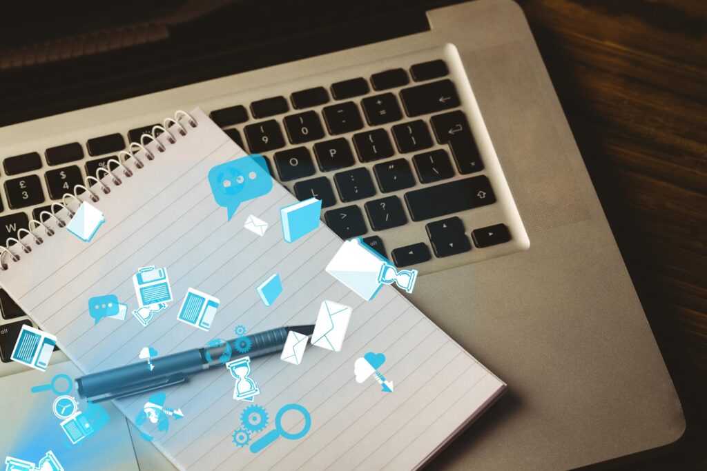 Un carnet et un stylo posés sur un ordinateur portable, avec des icônes numériques en surimpression représentant des messages, des documents et des outils collaboratifs.




